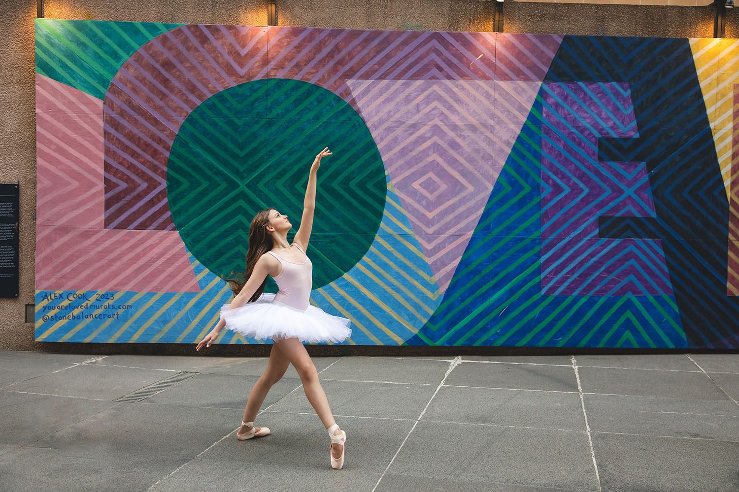 teenage dancer with light skin in ballet pose in front of a LOVE mural in downtown dallas - dallas dance photography