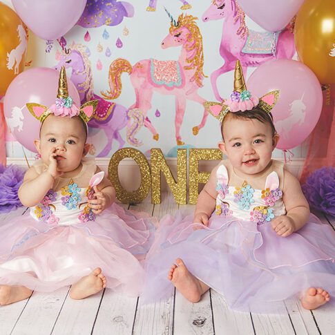 twin baby girls in pastel unicorn first birthday cake smash set